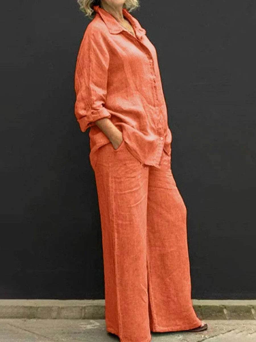 Woman wearing loose orange linen shirt and wide-leg trousers by ZA-Zola, black background