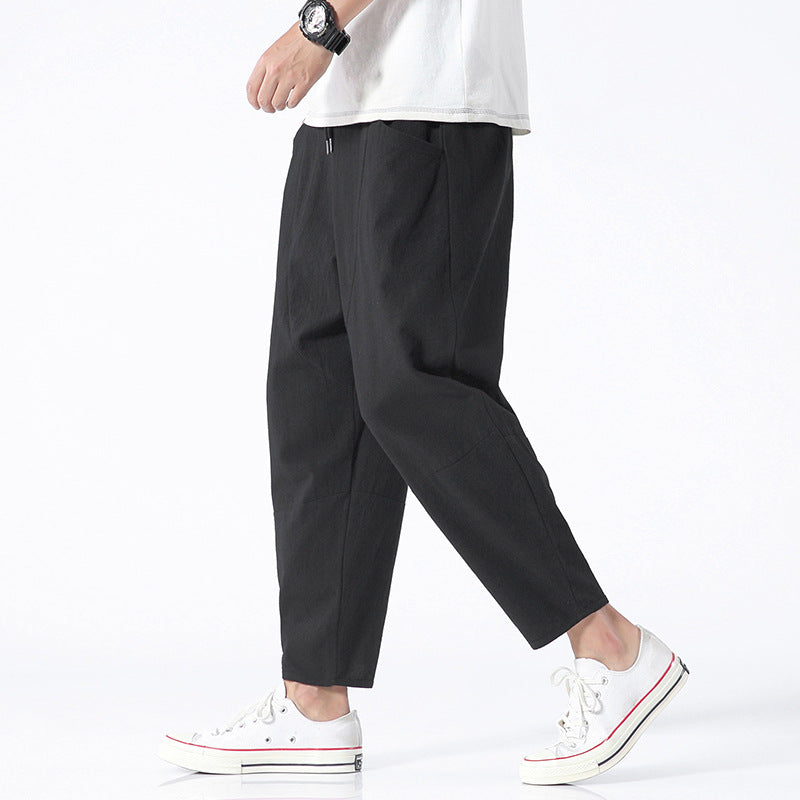 Person wearing black pants and white sneakers on a white background