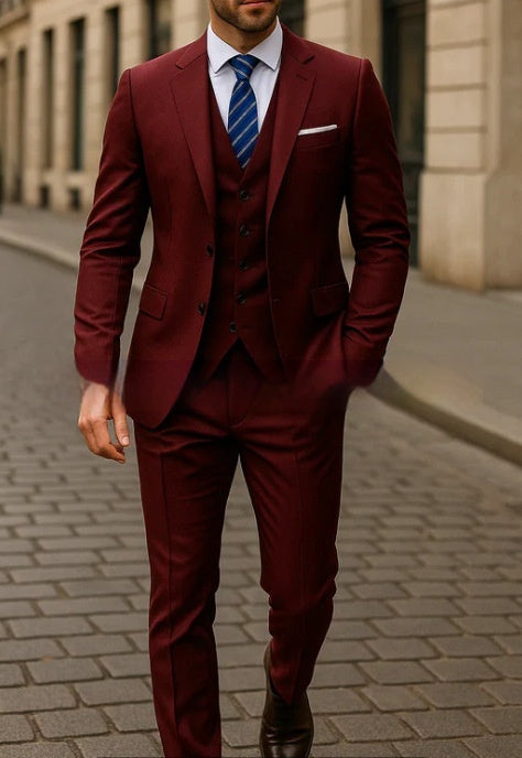 Man wearing a burgundy suit with a blue tie on a city street.