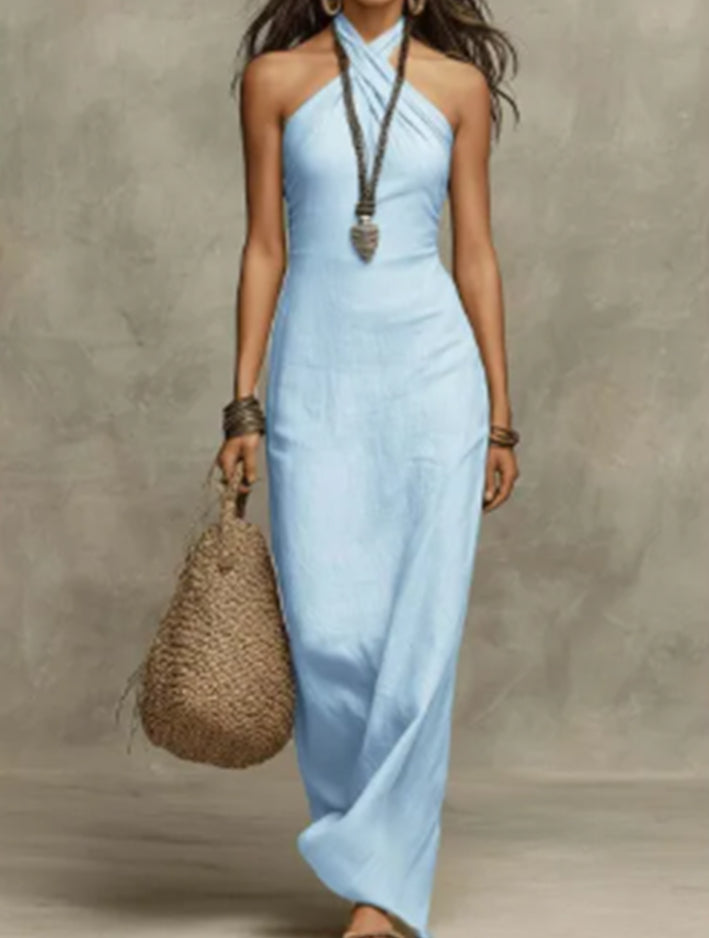 Woman wearing a light blue halter neck dress holding a woven bag against a neutral background