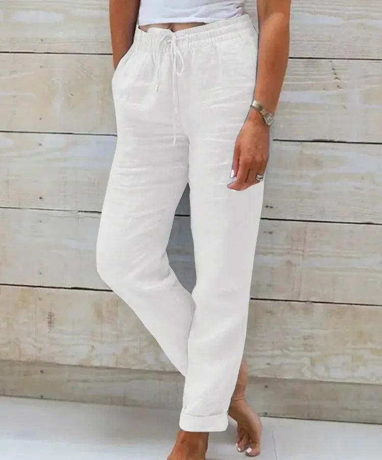 Person wearing white pants against a wooden background