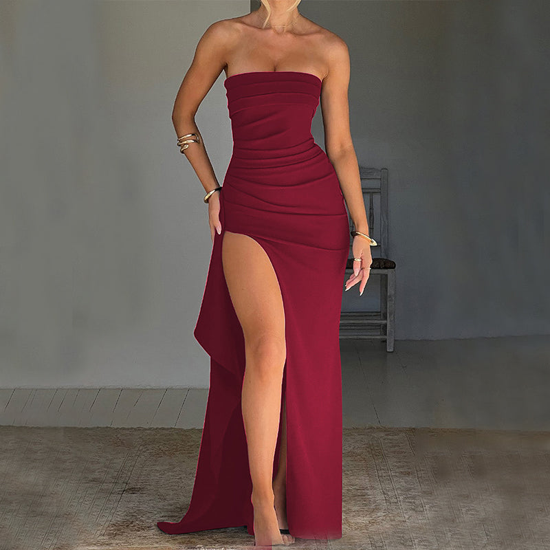 Woman wearing a strapless burgundy dress with a high slit in a minimalistic setting.
