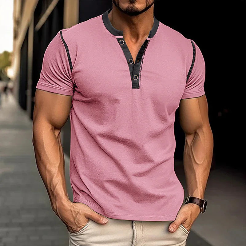 Man wearing a pink short-sleeve shirt with black accents on a blurred street background