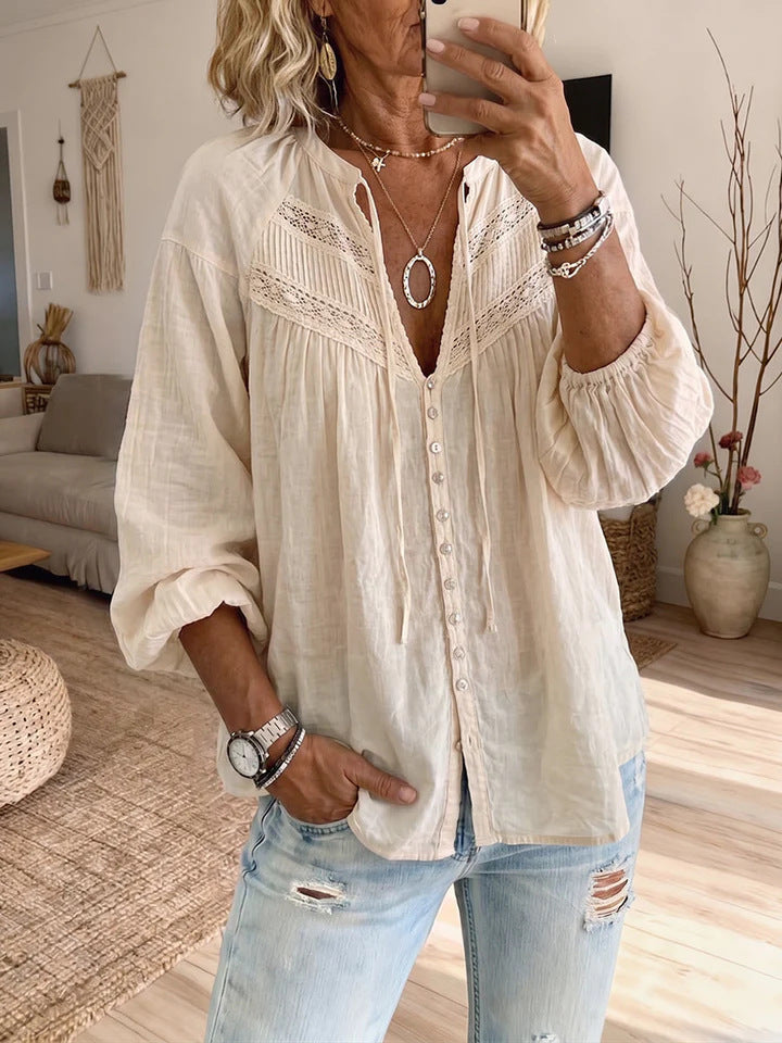 Woman wearing a white blouse with lace details and ripped jeans in a living room.