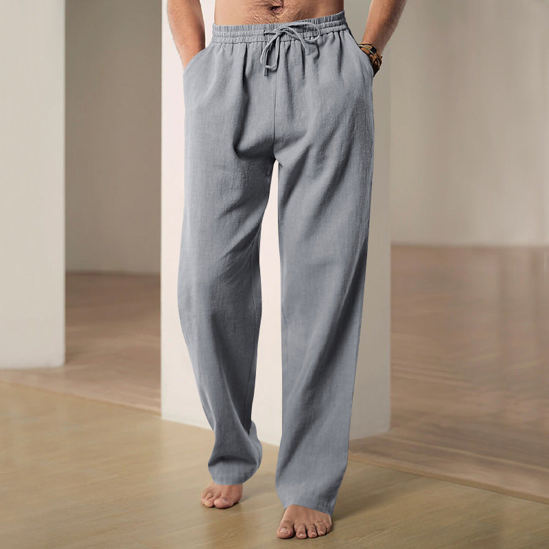 Person wearing light blue pajama pants standing in a minimalistic room.