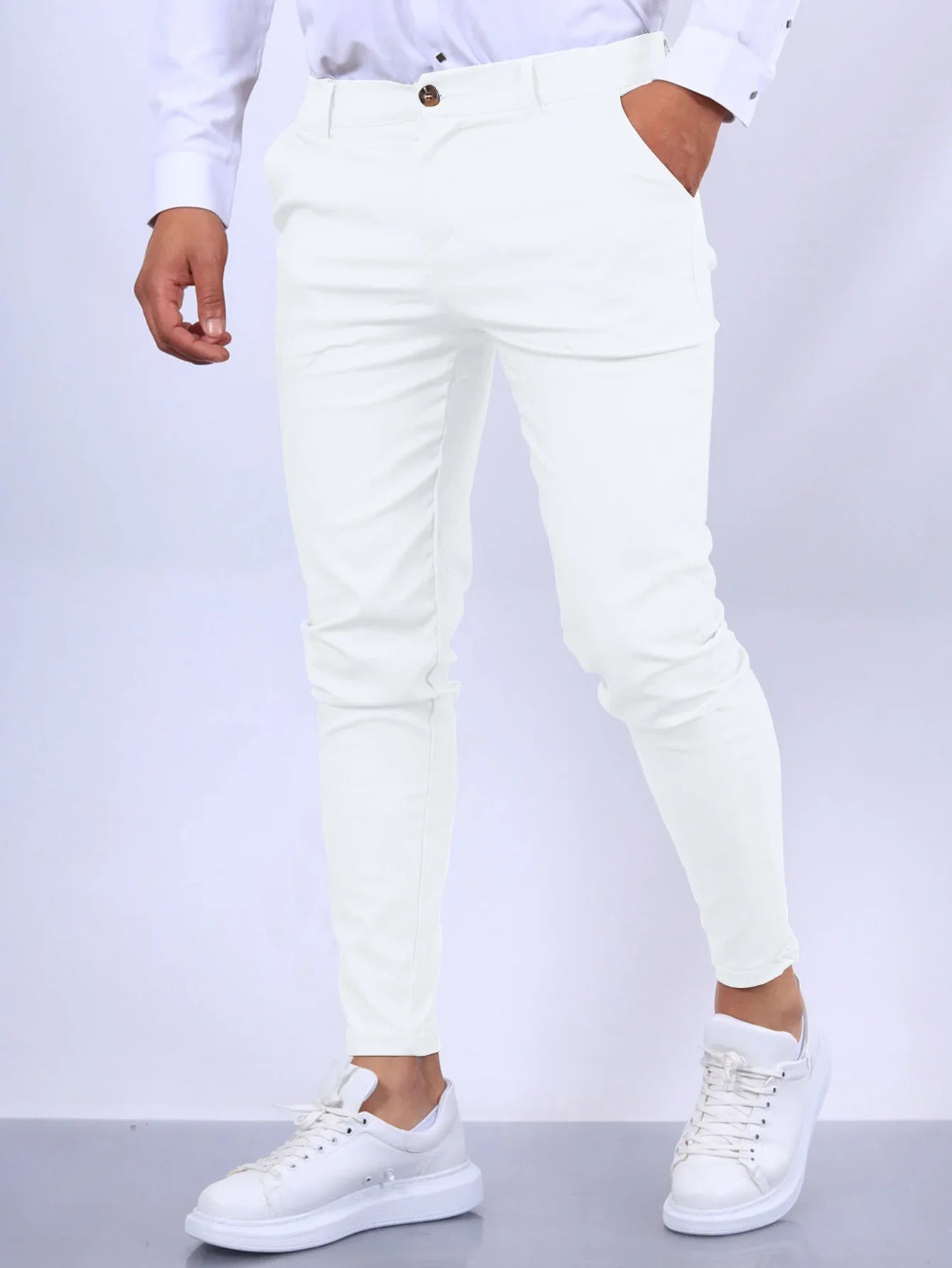 Person wearing white pants and white sneakers on a light gray background