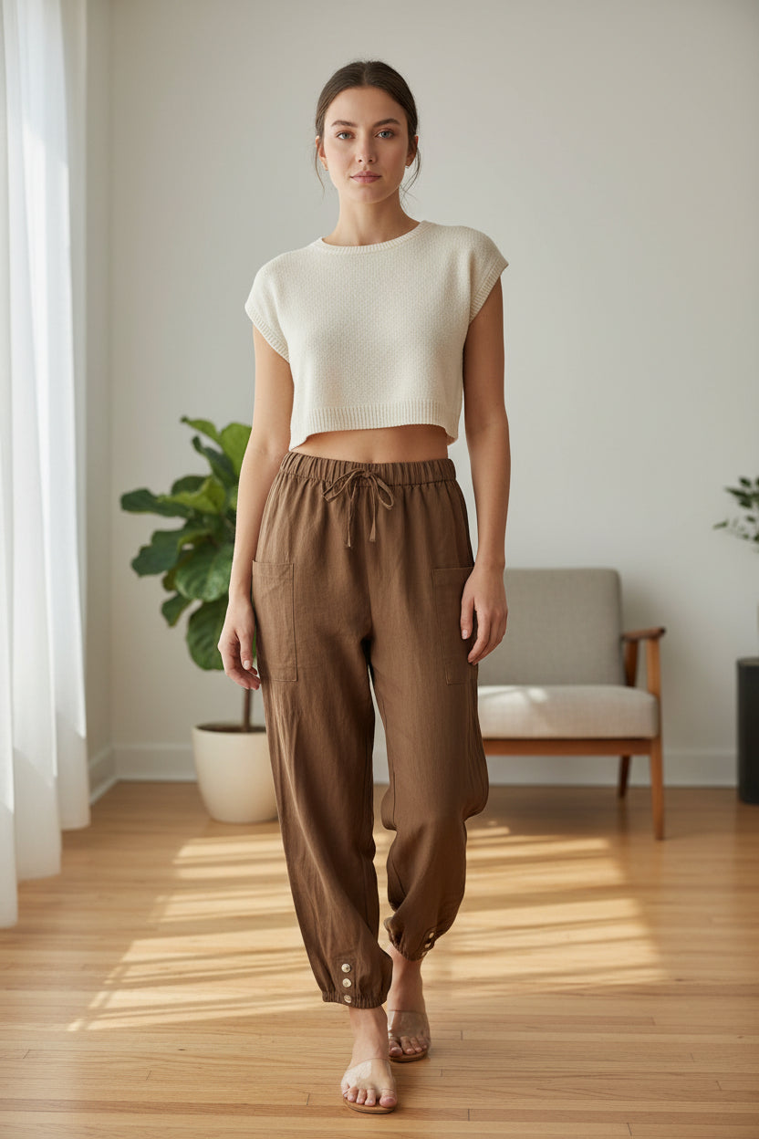 Brown pants with button details worn by models on a light wooden floor.