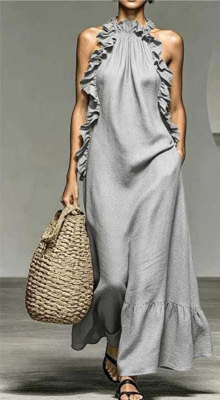 Woman wearing a gray dress holding a woven bag on a neutral background
