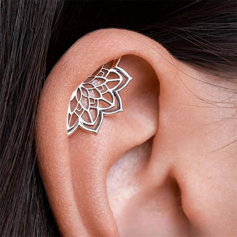 Silver ear cuff worn on an ear with dark hair background