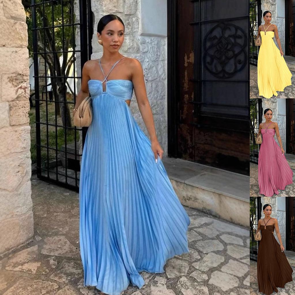 Woman in a blue pleated dress standing outdoors next to a stone wall.