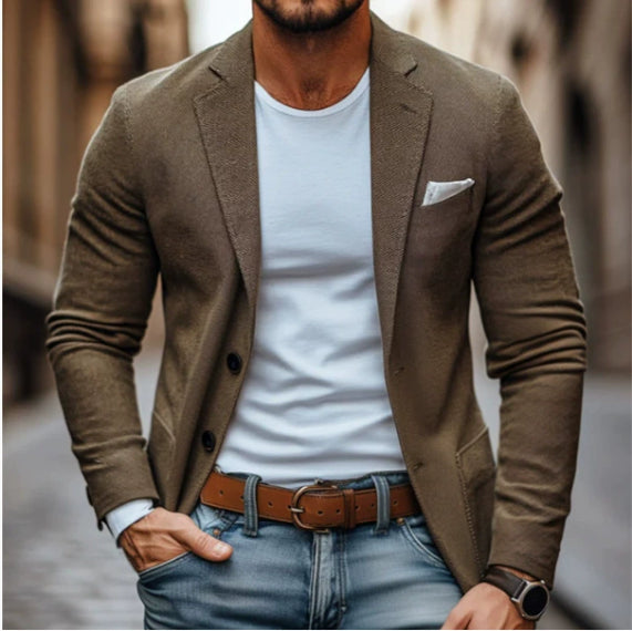 Man wearing a brown blazer over a white shirt with blue jeans.