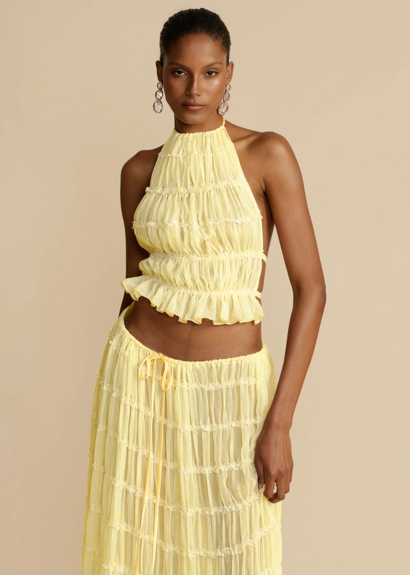Woman wearing a yellow ruffled dress against a beige background