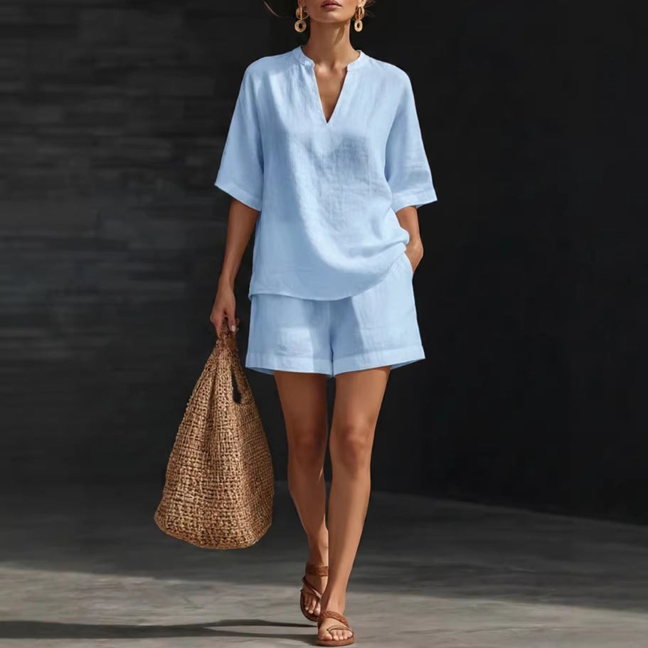 Woman in light blue outfit holding a woven bag against a dark background