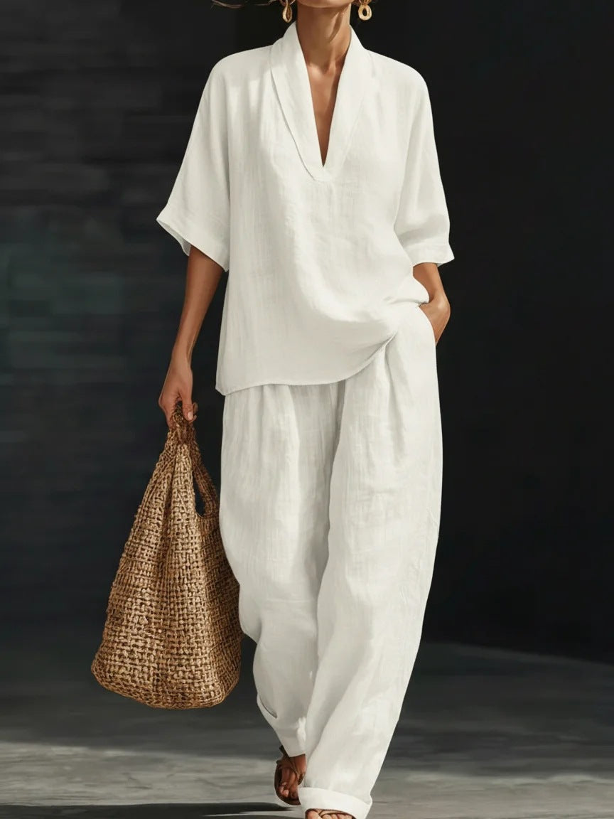 Person wearing a white outfit holding a woven bag against a dark background
