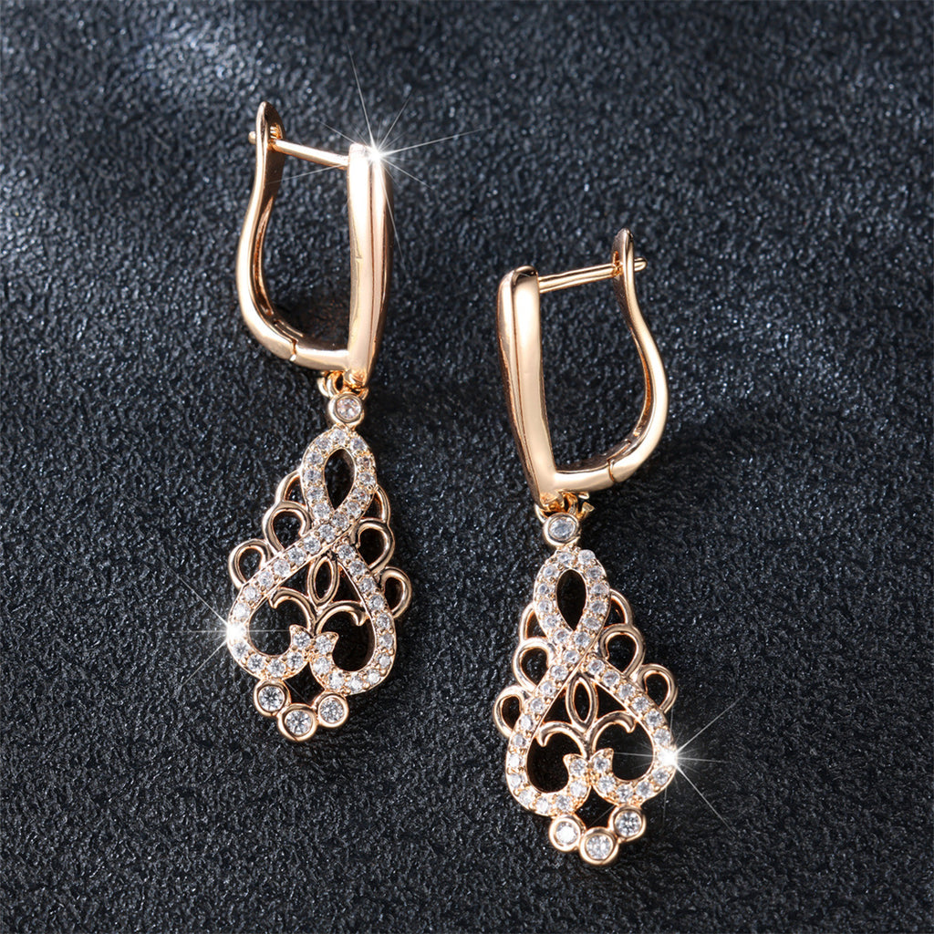 Pair of gold earrings with intricate designs on a dark background