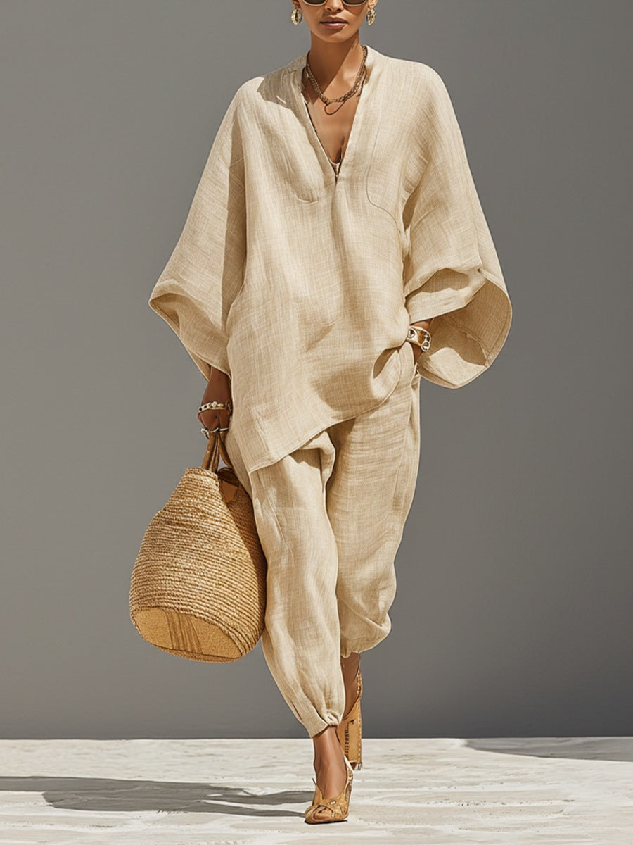Woman wearing a beige outfit holding a woven bag on a gray background