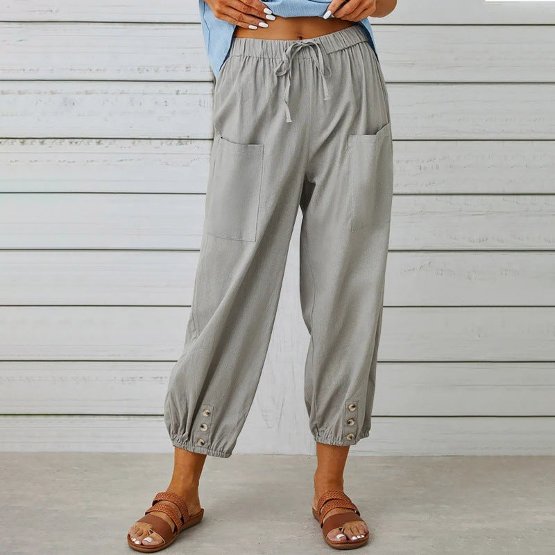 Person wearing gray drawstring pants with button details against a wooden background