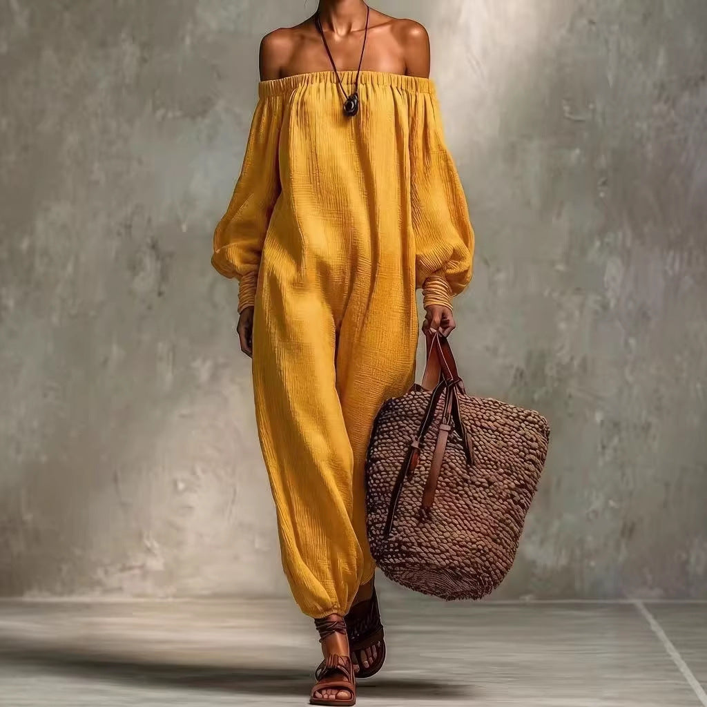 Person wearing a mustard yellow off-shoulder outfit holding a brown woven bag against a gray background