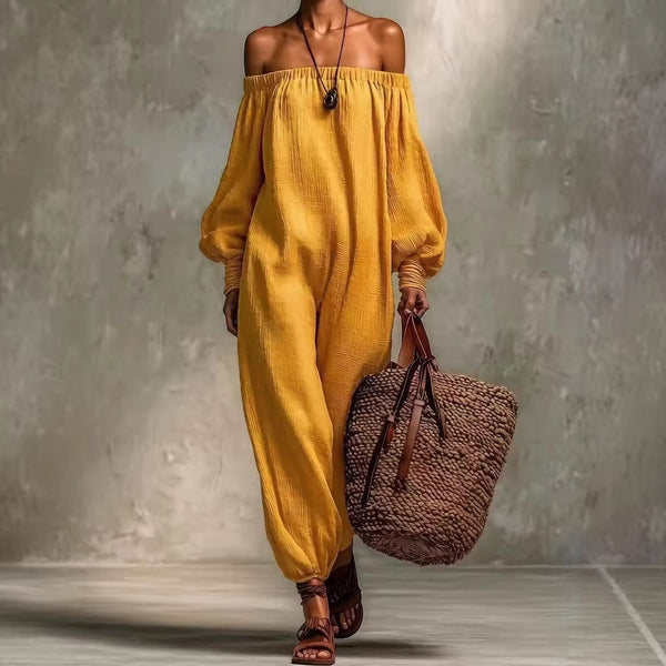 Person wearing a mustard yellow off-shoulder outfit holding a brown woven bag against a gray background