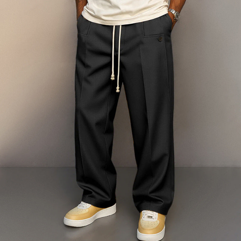 Person wearing black pants with a white shirt and yellow sneakers on a gray background