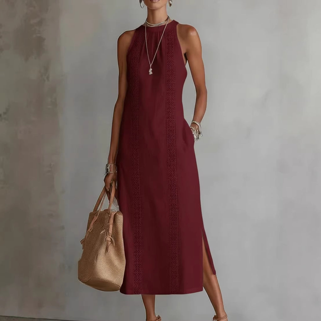 Woman wearing a burgundy dress holding a beige handbag against a plain background