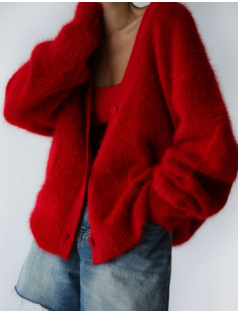 A person wearing a fuzzy bright red cardigan over a red top with blue jeans, photographed against a plain light background.