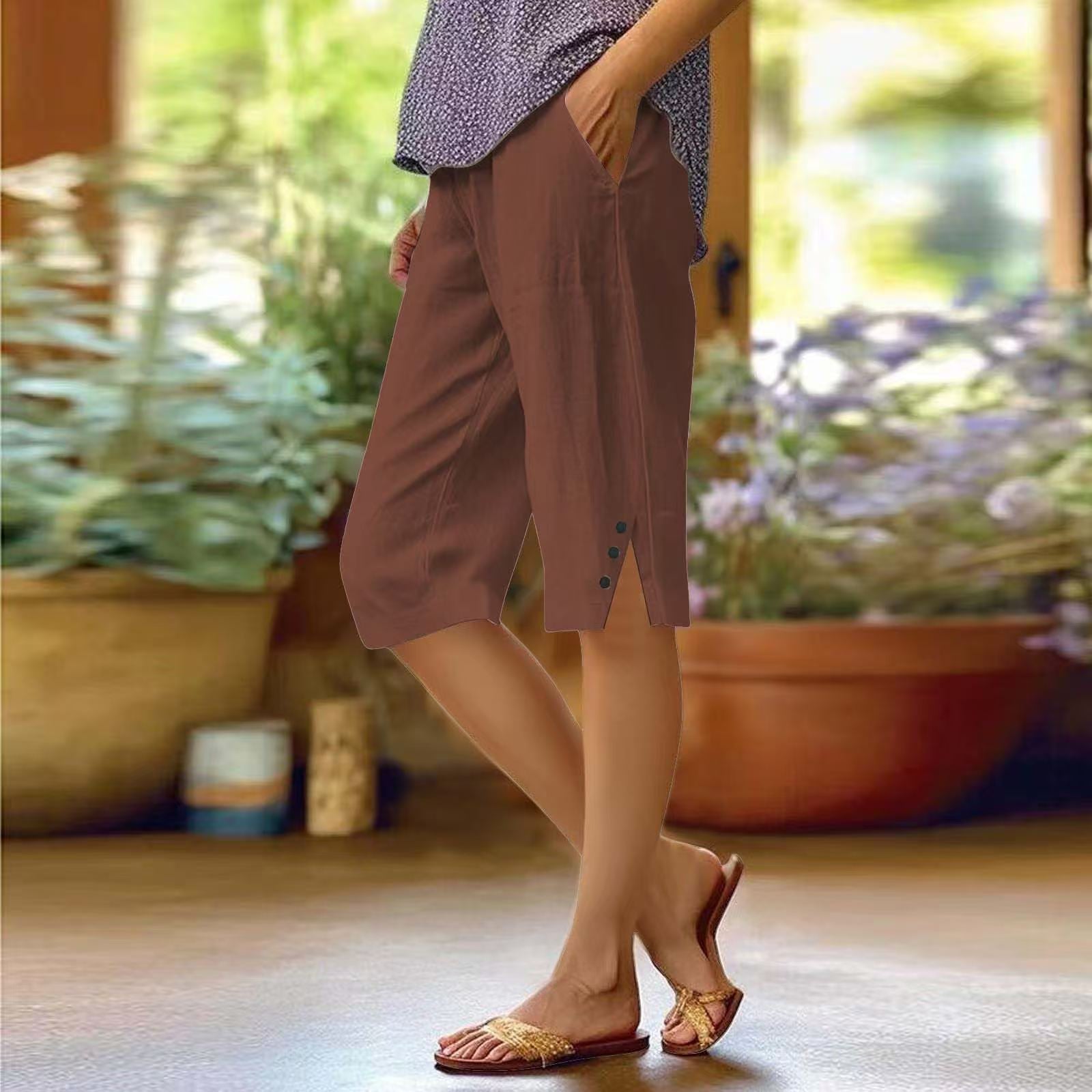 Person wearing brown shorts standing in a room with plants in the background