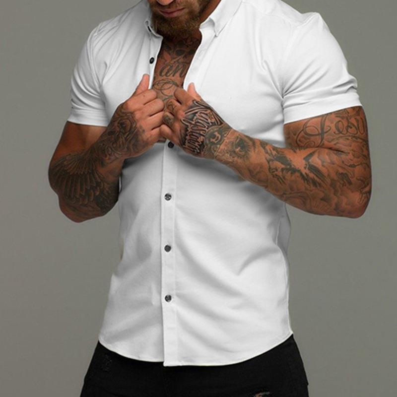 Man wearing a white short-sleeve shirt with tattoos on his arms against a gray background
