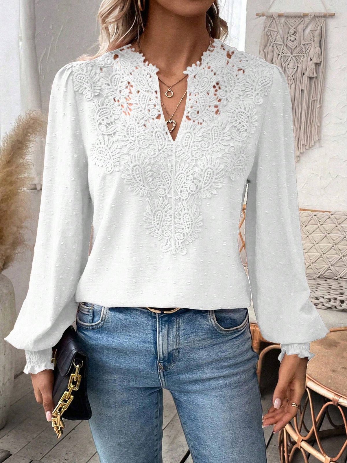 Person wearing a white lace blouse and blue jeans in a home setting