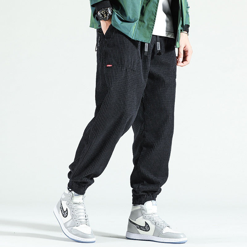 Person wearing black corduroy jogger pants with a white background