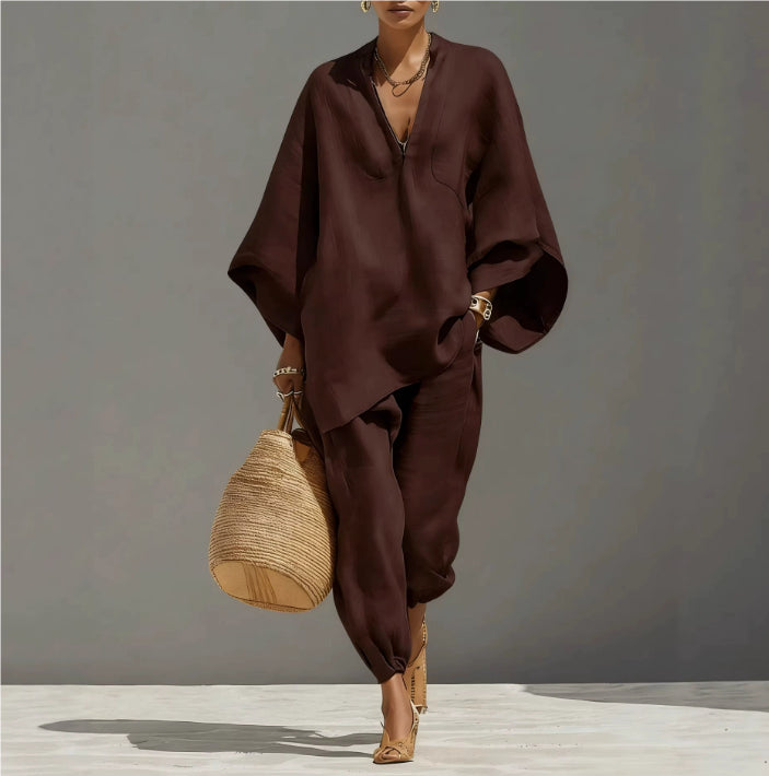 Person wearing a brown outfit holding a woven bag against a gray background