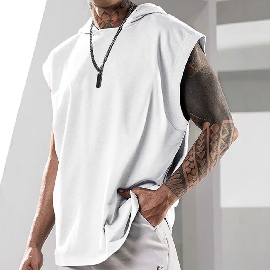 Person wearing a white sleeveless hoodie with tattoos on arms, standing against a light background