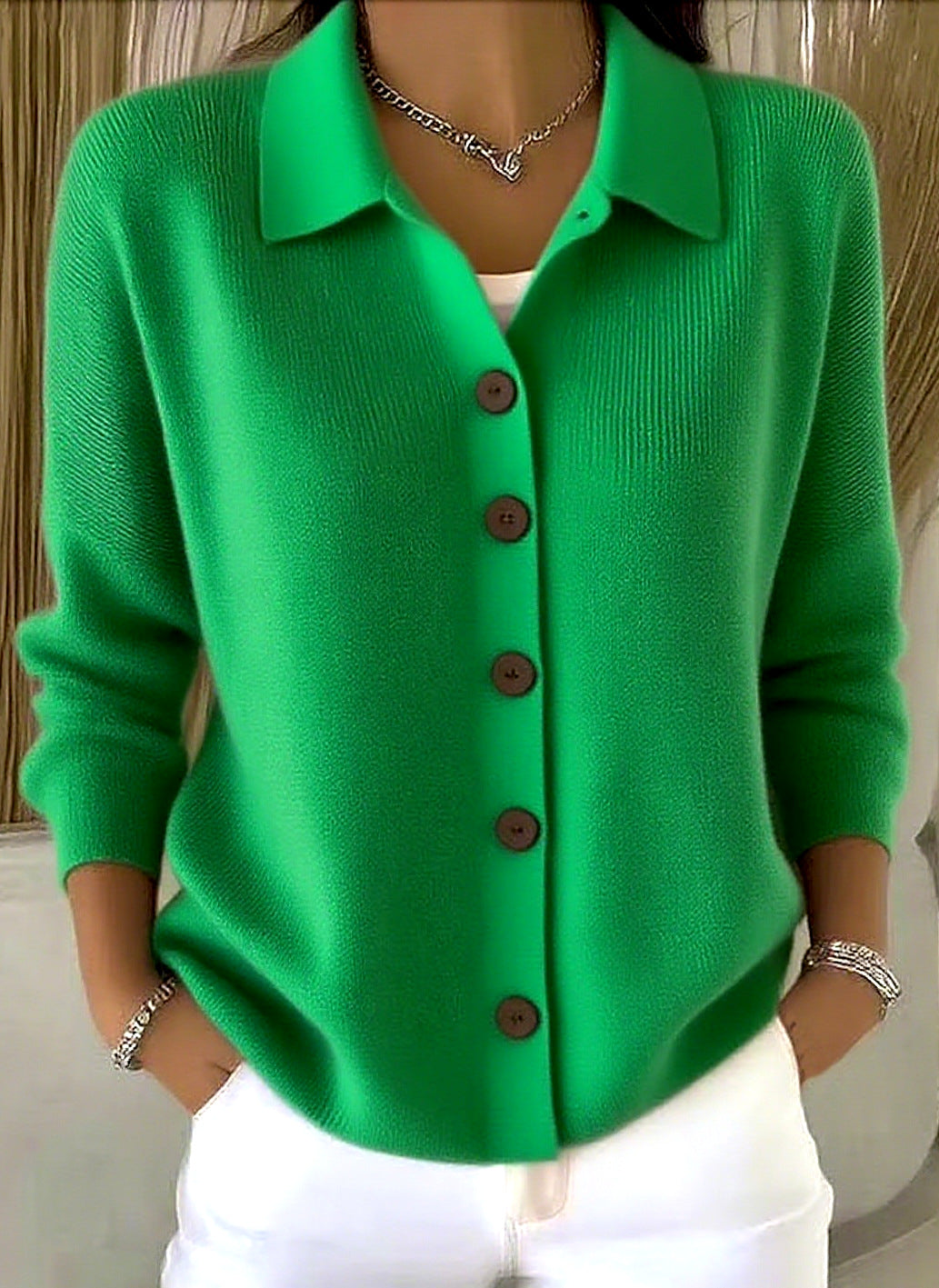 Green cardigan with buttons worn by a person, against a neutral background