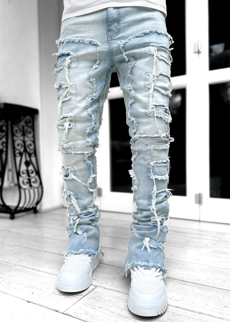Light blue ripped jeans worn by a person on a white floor.