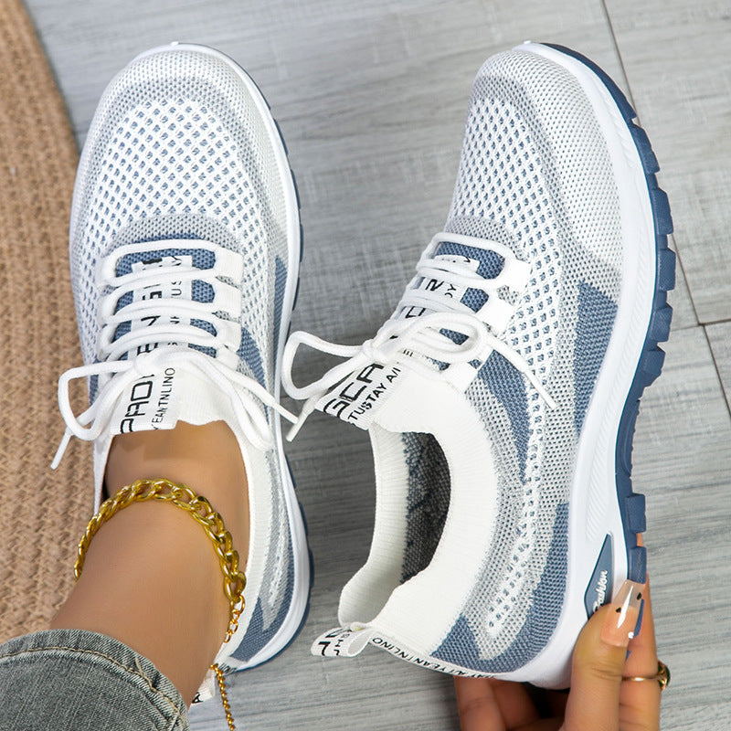 White and blue running shoes with visible branding on a wooden floor.