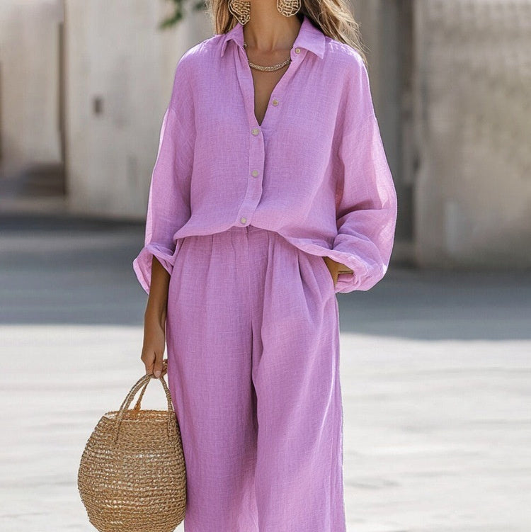 Person wearing a pink outfit with wide-leg pants and holding a straw bag.