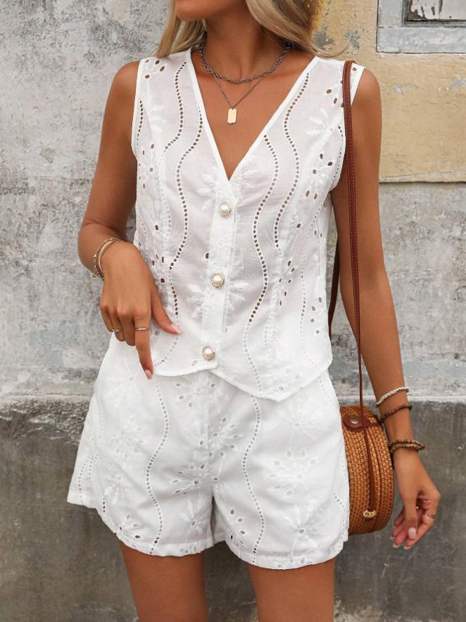 Woman wearing a white sleeveless top and shorts set against a textured wall.