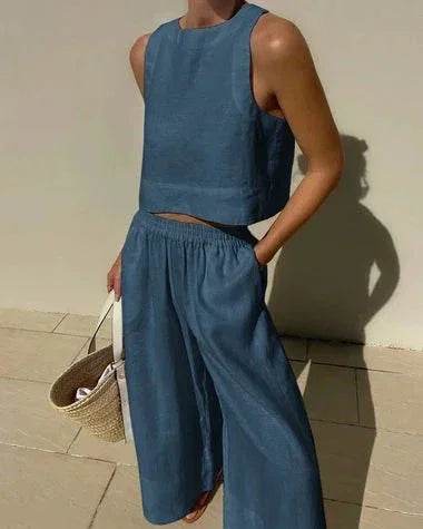 Woman in blue sleeveless crop top and wide-leg pants, holding straw bag, ZA-Zola fashion.