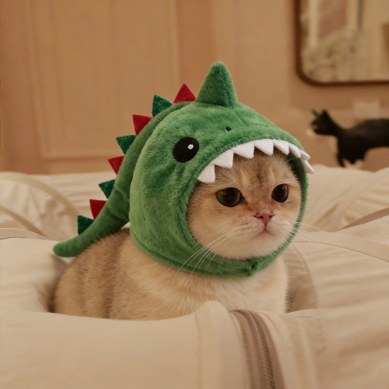 Cat wearing a green dinosaur costume on a bed