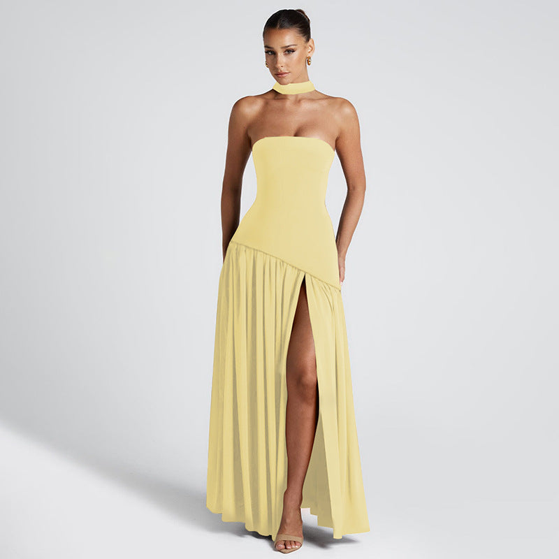 Woman wearing a yellow strapless gown with a slit on a light gray background