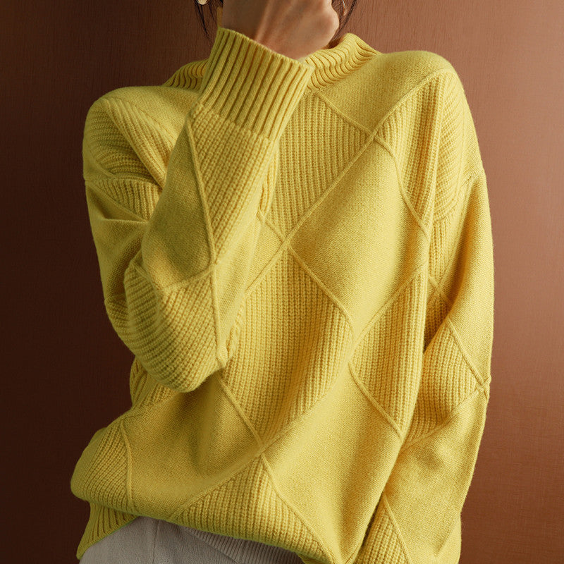 A person wearing a bright yellow knit sweater with a diamond cable pattern, photographed against a warm brown background.