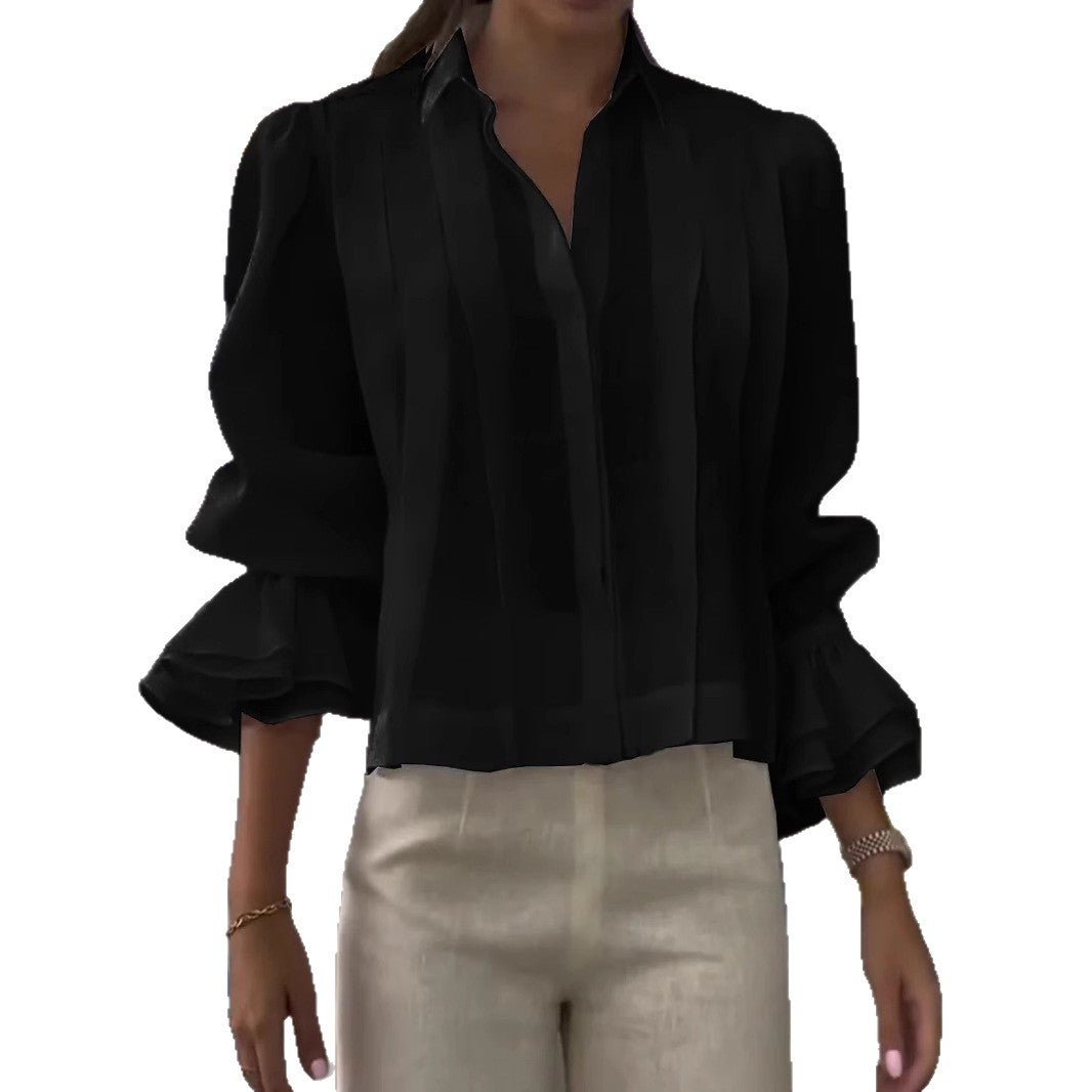 Black blouse with ruffled sleeves worn by a person on a white background