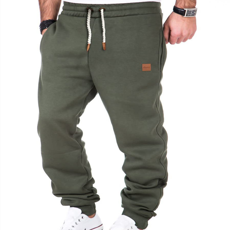 Green sweatpants with a small brown logo tag on a white background