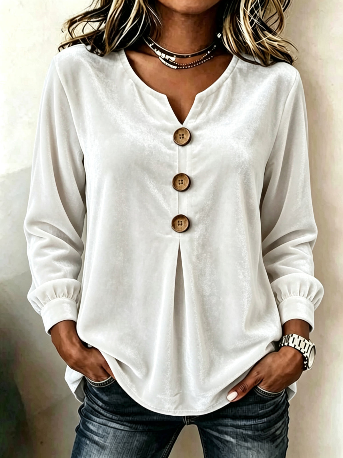 White blouse with wooden buttons worn by a person against a neutral background