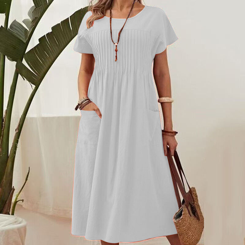 Woman wearing a light blue dress holding a straw bag with a plant in the background