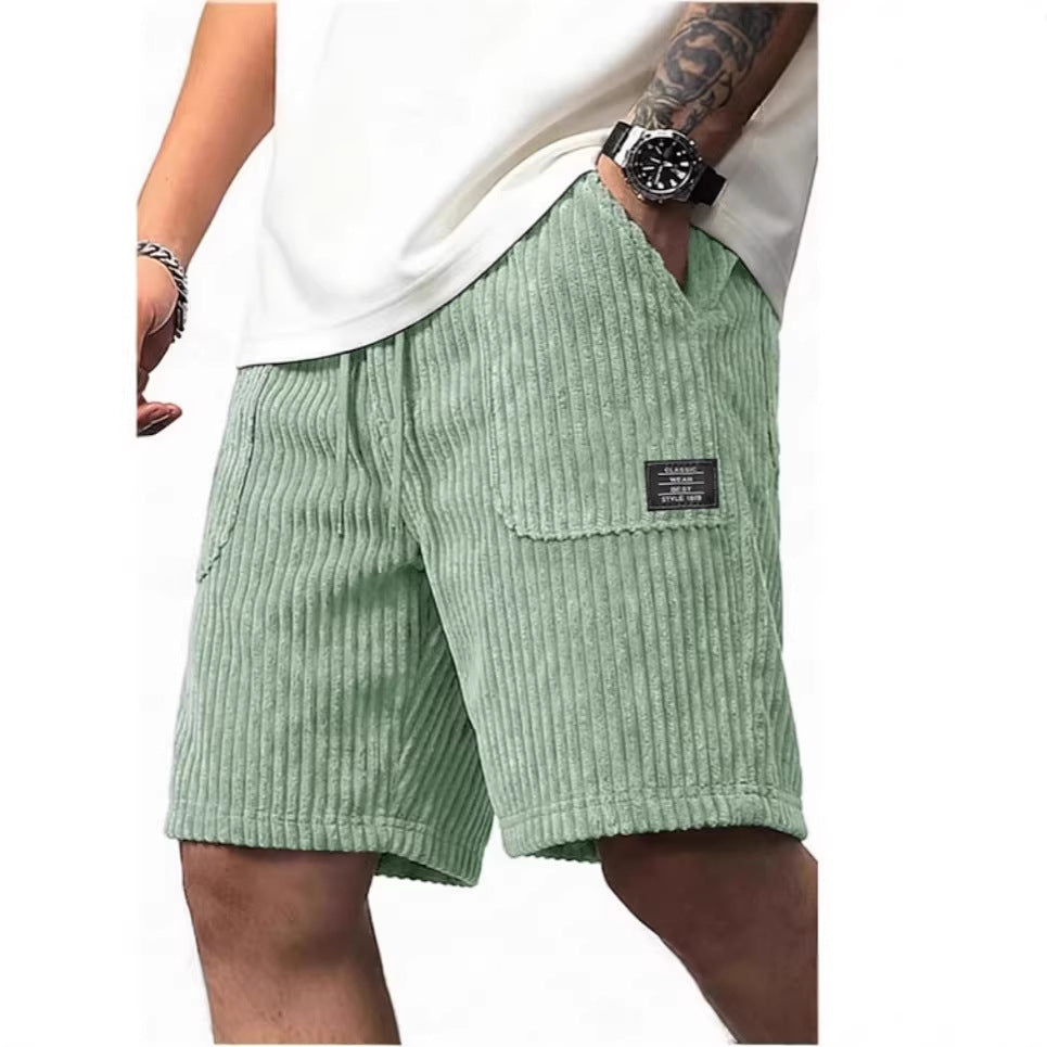 Green corduroy shorts worn by a person on a white background