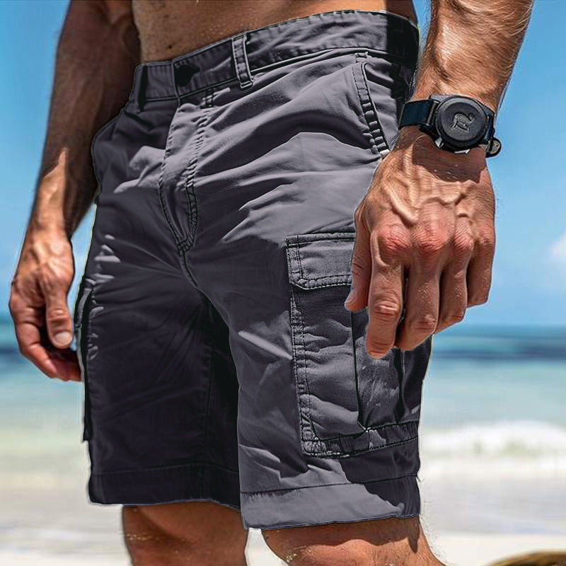Person wearing gray cargo shorts with a blurred beach background