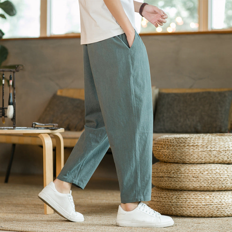 Person wearing green pants and white sneakers in a room with a sofa and decorative items.