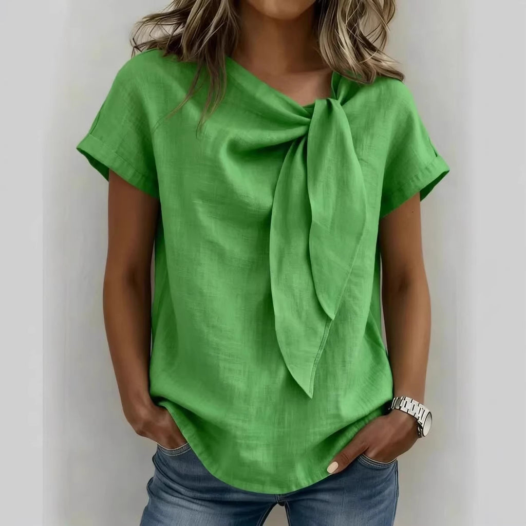 Person wearing a green top with a scarf tied around the neck against a white background
