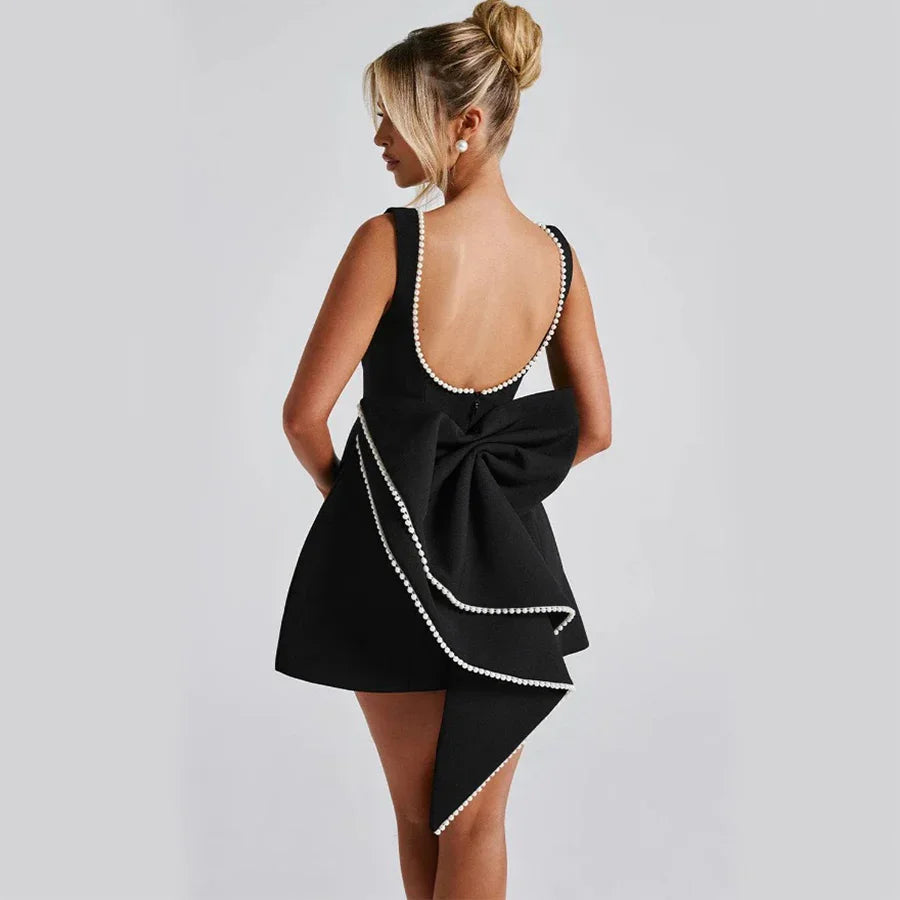 Black dress with a large bow detail on a plain background